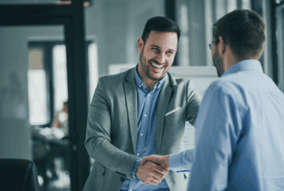 Two business professionals shaking hands in an office, representing trust, collaboration and confidence in business information Two business professionals shaking hands in an office, representing trust, collaboration and confidence in business information